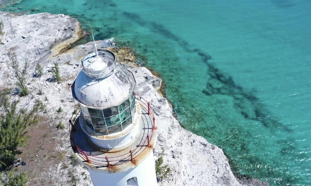 Aerial view of a Bahamian lighthouse beside turquoise sea